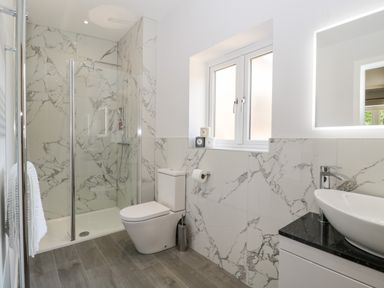 A bathroom with a shower enclosure toilet sink and a window at Stag Cottage in Lytchett Matravers
