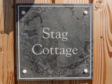 A slate sign with the text Stag Cottage mounted on wooden surface at Stag Cottage in Lytchett Matravers