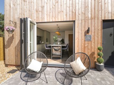 A patio with two chairs and cushions outside a kitchen at Stag Cottage in Lytchett Matravers