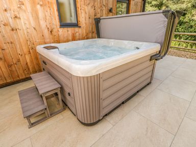 An outdoor hot tub with steps beside a wooden wall at Stag Cottage in Lytchett Matravers