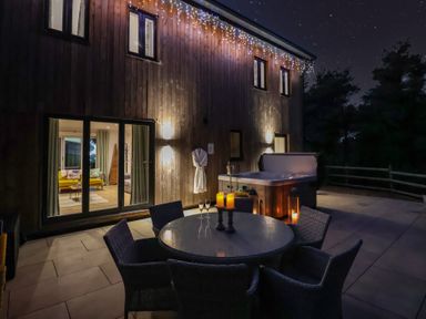 An outdoor area with a dining table and hot tub at Stag Cottage in Lytchett Matravers