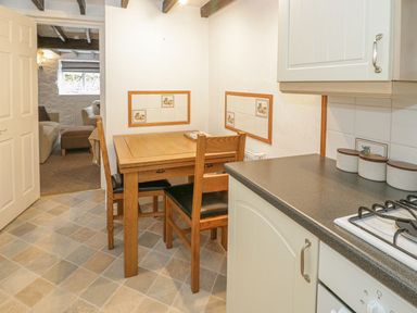 A kitchen with a wooden table and chairs and a countertop with canisters at Ty Coed in Beaumaris
