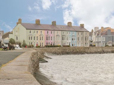A row of multi colored houses along a stone seawall by the water at Ty Coed in Beaumaris