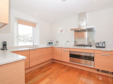 A kitchen with wooden cabinets a gas stove a microwave and a window at 15 Dart Marina in Dartmouth