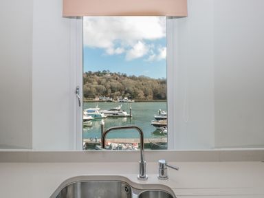 A kitchen sink with a faucet and window showing boats on water and a hillside at 15 Dart Marina in Dartmouth