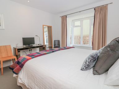 A bedroom with a double bed a desk with a computer monitor a mirror and two chairs at 15 Dart Marina in Dartmouth