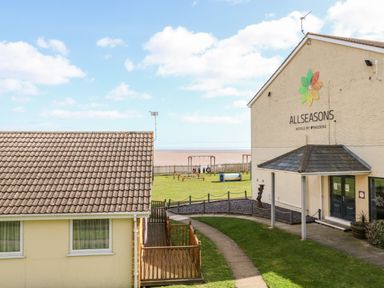 A view of a hotel building with a play area and path leading to the beach at All Seasons in Corton