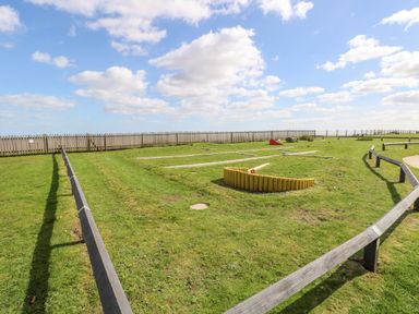 An outdoor mini golf course with green grass and wooden fences at Bungalow 14 in Corton