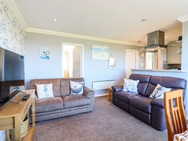 A living room with two sofas a wooden TV stand and wall art at Bungalow 14 in Corton