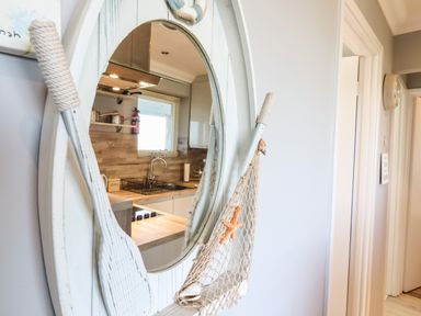 A kitchen reflected in a mirror with white walls and doorways at Bungalow 14 Corton