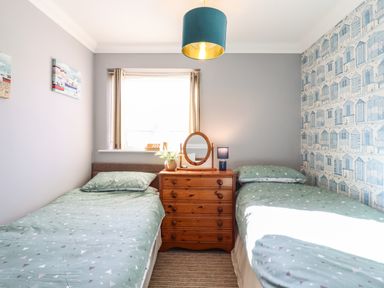 A bedroom with two single beds a wooden chest of drawers and a window at Bungalow 14 in Corton