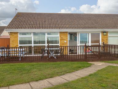 A bungalow with a tiled roof a wooden deck and outdoor furniture at Bungalow 14 in Corton