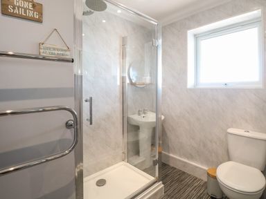 A bathroom with a glass shower enclosure a pedestal sink a toilet and a window at Bungalow 14 in Corton