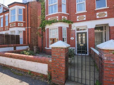 A brick townhouse with a black front door behind a metal gate at Apple Tree House in Hunstanton