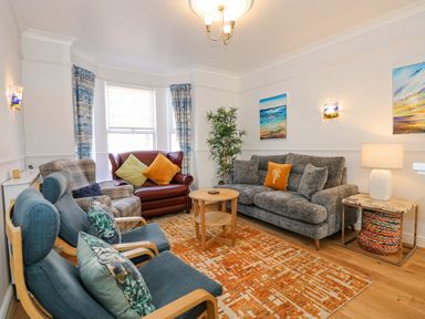 A living room with sofas armchairs a coffee table and colorful cushions at Apple Tree House in Hunstanton