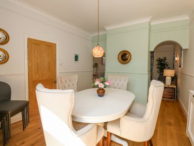A dining room with a white round table and four chairs with a flower vase on the table at Apple Tree House in Hunstanton