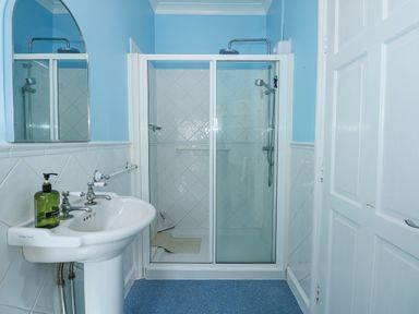 A bathroom with a pedestal sink a mirror and a glass-enclosed shower at Apple Tree House in Hunstanton