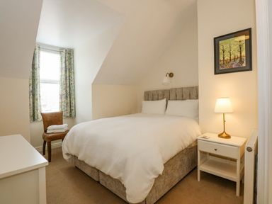 A bedroom with a double bed chair with towels bedside table lamp and framed picture at Apple Tree House in Hunstanton