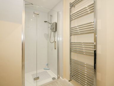 A shower area with glass doors and a chrome heated towel rail at Apple Tree House in Hunstanton