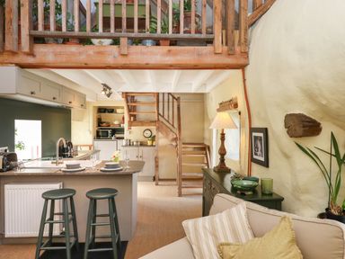 A kitchen and living area with wooden stairs plants and a sofa at The Byre in Monkleigh near Great Torrington