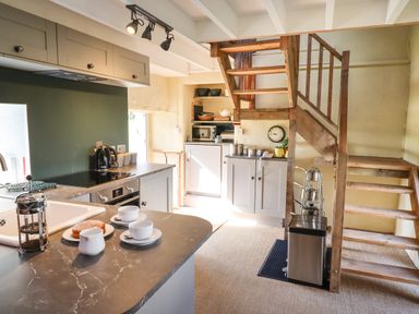 A kitchen with wooden stairs a countertop with cups a coffee maker and an oven at The Byre in Monkleigh near Great Torrington