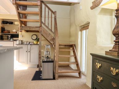 A kitchen area with wooden stairs and a black chest of drawers at The Byre in Monkleigh near Great Torrington