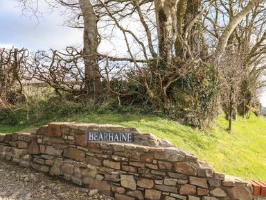 A stone wall with a sign that reads Bearhaine next to a grassy area with leafless trees at The Byre in Monkleigh near Great Torrington