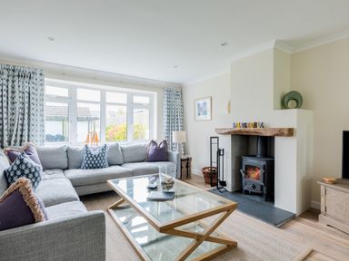 A living room with a large gray sectional sofa and a glass coffee table in front of a fireplace with a wood stove at Silverdale in Rock