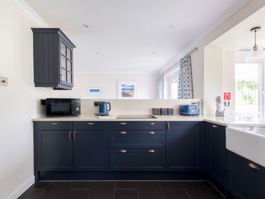 A kitchen with blue cabinets a microwave kettle toaster and a knife block at Silverdale in Rock
