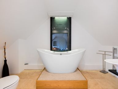 A bathroom with a freestanding bathtub on a wooden platform and a mirror at Silverdale in Rock