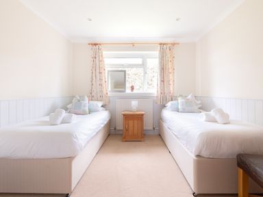 A bedroom with two single beds a wooden nightstand and floral curtains at Silverdale in Rock