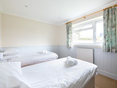 A bedroom with two single beds with white linens and rolled towels near a window with curtains at Silverdale in Rock