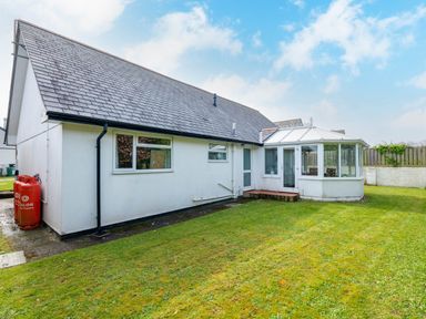 A white single-story house with a sloped roof and a conservatory attached at Silverdale in Rock