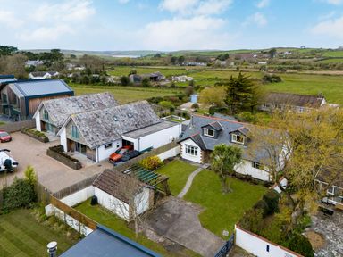 Aerial view of houses with gardens, trees, cars, and surrounding fields at Silverdale in Rock