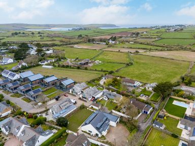 An aerial view of houses with gardens and fields with hills and water in the background at Silverdale in Rock