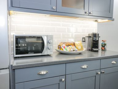 A kitchen counter with a microwave, a plate of groceries, and a coffee machine at The Lazy Seal in Spittal