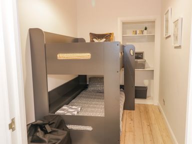 A small bedroom with a dark bunk bed wooden floor and shelving at The Lazy Seal in Spittal