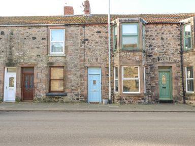 A row of stone terraced houses with different colored doors on a street at The Lazy Seal in Spittal