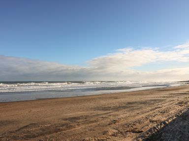 A sandy beach with waves and a partly cloudy sky at The Lazy Seal in Spittal