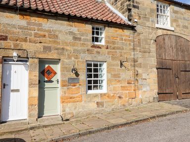 Stone building facade with two windows two doors and wooden barn doors at Michaelmass Cottage in Castleton