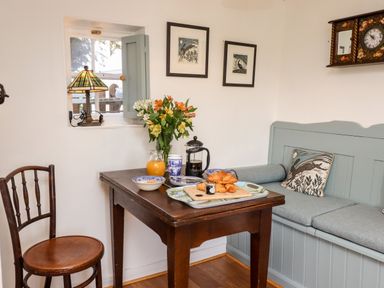 A dining area with a wooden table set for breakfast and seating at Michaelmass Cottage in Castleton