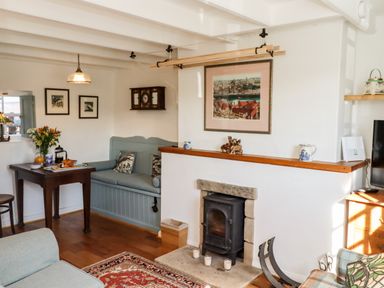 A living room with a wood stove fireplace a built in bench and a small dining table at Michaelmass Cottage in Castleton