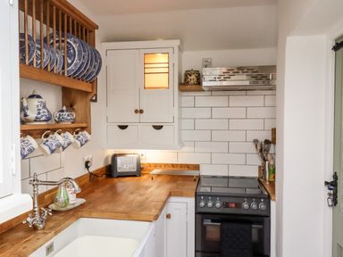 A kitchen with a wooden countertop stove and hanging blue and white dishes at Michaelmass Cottage in Castleton