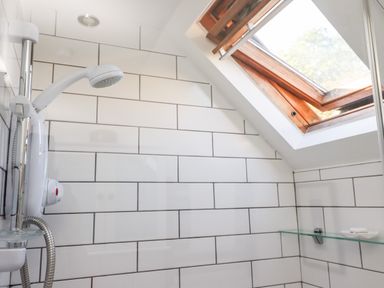 A shower area with white tiled walls and a skylight window at Michaelmass Cottage in Castleton
