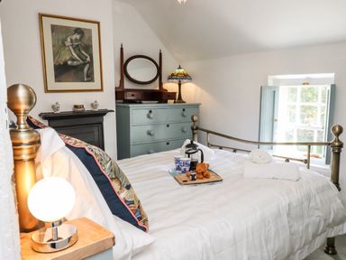 A bedroom with a brass bed and breakfast tray on the bed at Michaelmass Cottage in Castleton