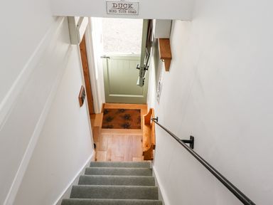 A staircase with a green half door at the bottom and a wooden handrail at Michaelmass Cottage in Castleton
