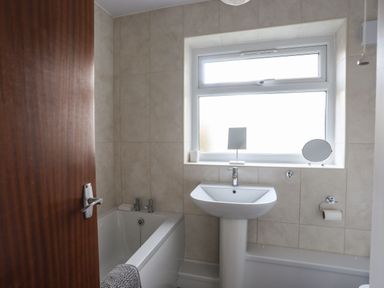 A bathroom with a bathtub a sink and a window at 5 Ger Y Nant in Llanbedrog