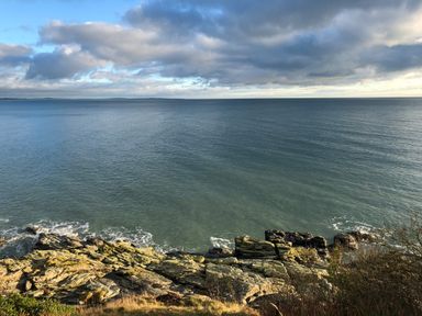 A rocky coastline with waves hitting the shore under a cloudy sky at Rocklea Seaside Cottage Newcastle County Down