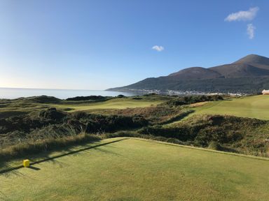 A golf course near the ocean with hills in the background at Rocklea Seaside Cottage in Newcastle County Down