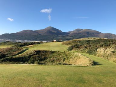 A golf course with hills and bushes a town and mountains in the background at Rocklea Seaside Cottage in Newcastle County Down